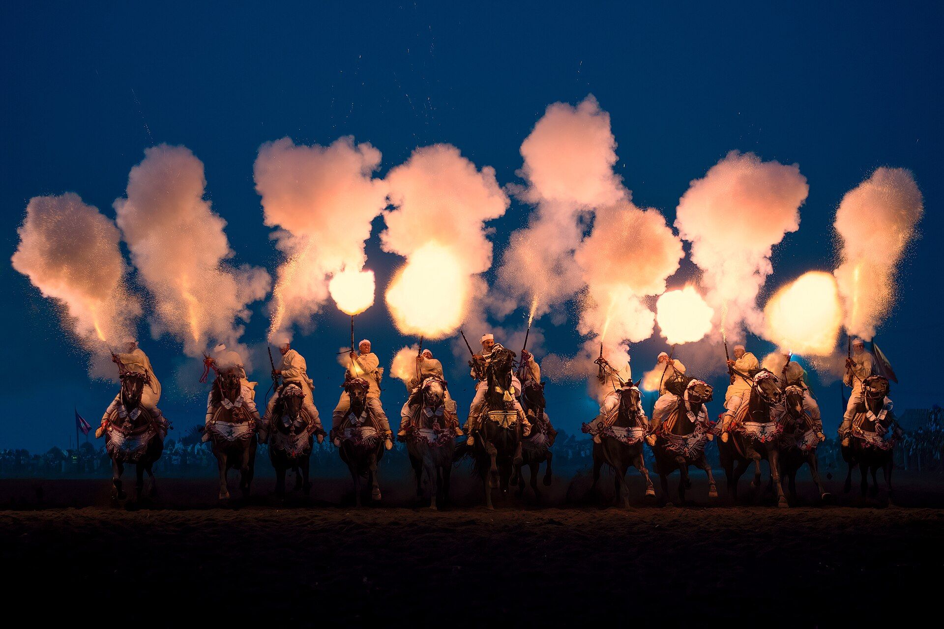 Cavaliers de tbourida et salve de fusils à la tombée de la nuit